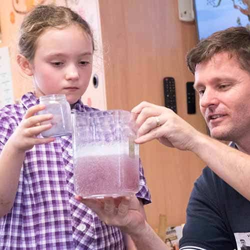 A student watching a purple liquid fizz