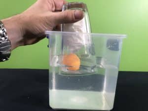 Air takes up space science experiment - beginning to push the glass over the floating ping pong ball
