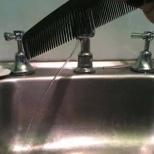 A plastic comb bending a stream of water coming out of a kitchen tap