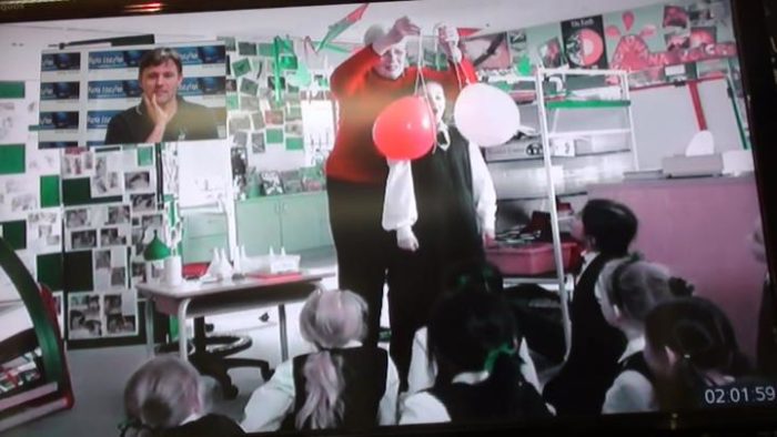 Blow em apart science experiment - student blowing apart balloons during a Fizzics video conference