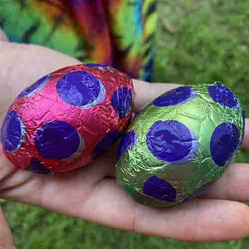 A purple and a green Easter eggs in a palm of a hand