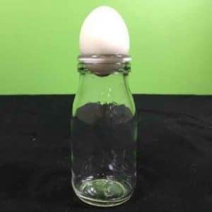 Egg sitting on top of a glass bottle