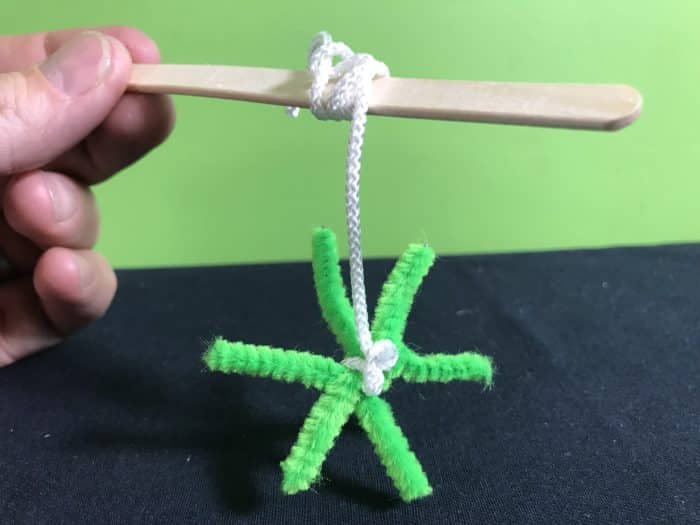 Make a borax snowflake science experiment - hanging a star shae pipecleaner from a ice cream stick