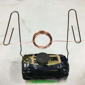 A coil of wire suspended over a D battery by two paperclips
