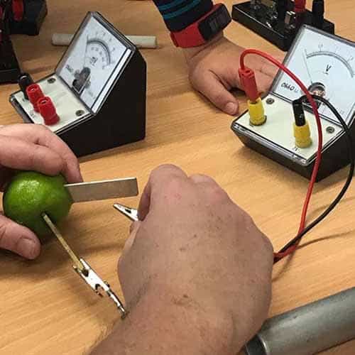 Lemons and limes with different metals in them, with electrodes connected and leading to voltmeters