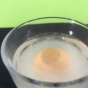 An egg floating in salt water in a glass (overhead view)