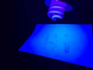 Secret glow in the dark science experiment - secret message on paper revealed under a UV black light