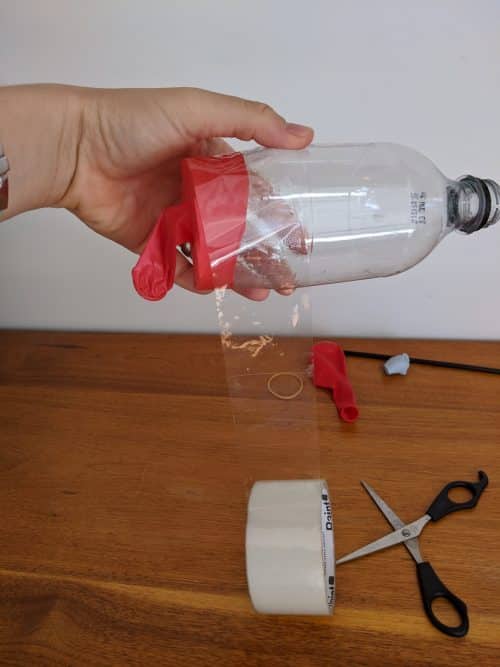 Wrapping sticky tape around the end of a plastic bottle that has a balloon diaphragm attached