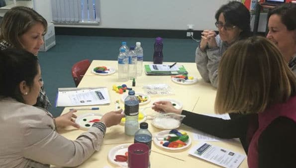 multiple teachers surrounding a table full of science experiment