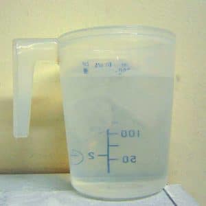 a measuring cup with ice floating in the water