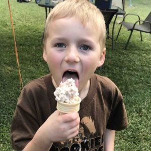 A child biting into a chocolate ice cream
