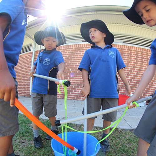 Students dipping bubble wands into buckets