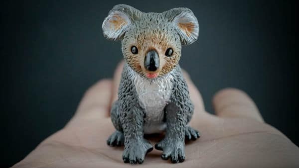 Koala replica sitting on the palm of a hand. Front view