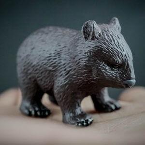 Person holding in the palm of their hand a replica of a common wombat