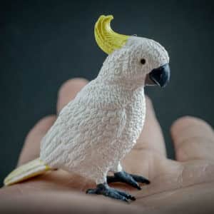 Sulfur-crested Cockatoo replica standing on a hand. Side view