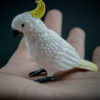 Sulfur-crested Cockatoo replica standing on a hand. Side view