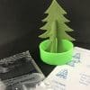green cardboard tree in a green cup with the instructions to the right side and a clear liquid substance in a clear packet