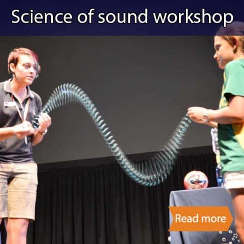Two people shaking a slinky on stage which has made it form a wave shape