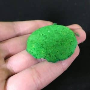A green crumbly ball of powder in someone's hand