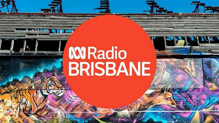 red logo with white text in the middle saying radio Brisbane with street art in the background