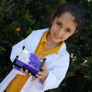 Close up of Girl in a lab coat holding a science toy