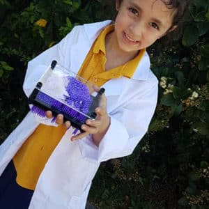 Girl in a lab coat holding a science toy