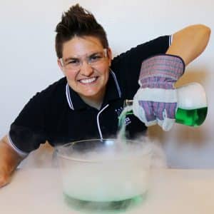 a lady with a black shirt pouring liquid nitrogen into a bowl
