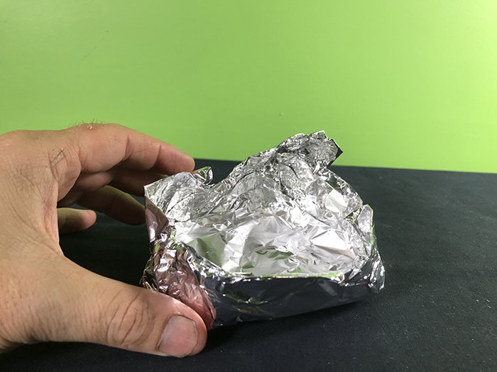 Guy making a foil boat on a black table