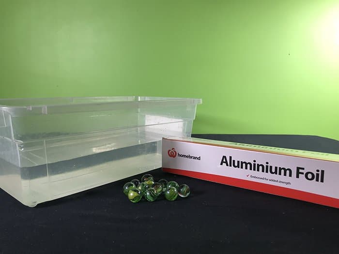 The equipment used for this experiment are shown, Plastic half full of water, marbles and Aluminium Foil.