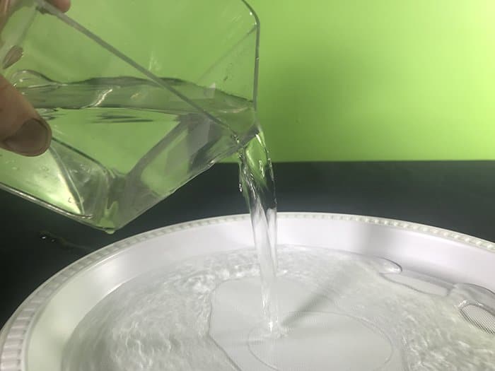 Water from a Jug getting poured into a plastic bowl