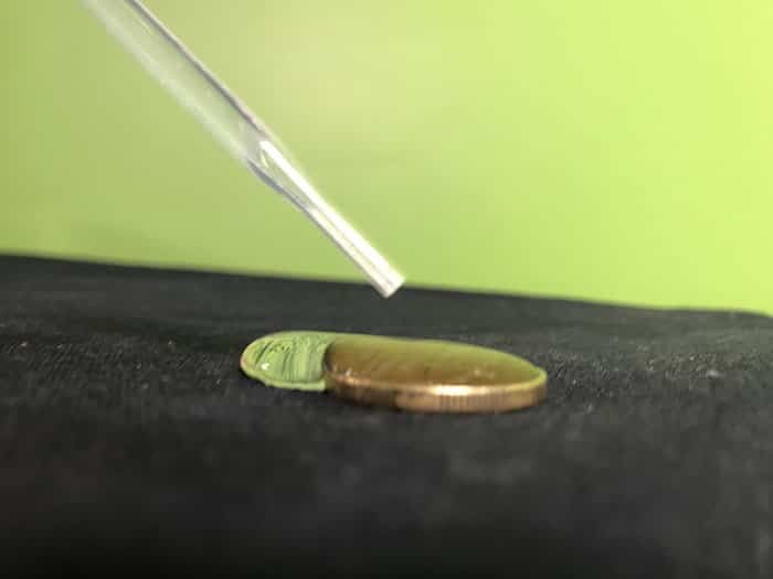 Water dropping out of a pipette onto a coin, drops of water dropping off the coin