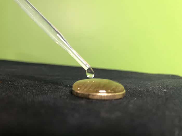 Water dropping out of a pipette onto a coin, multiple drops of water