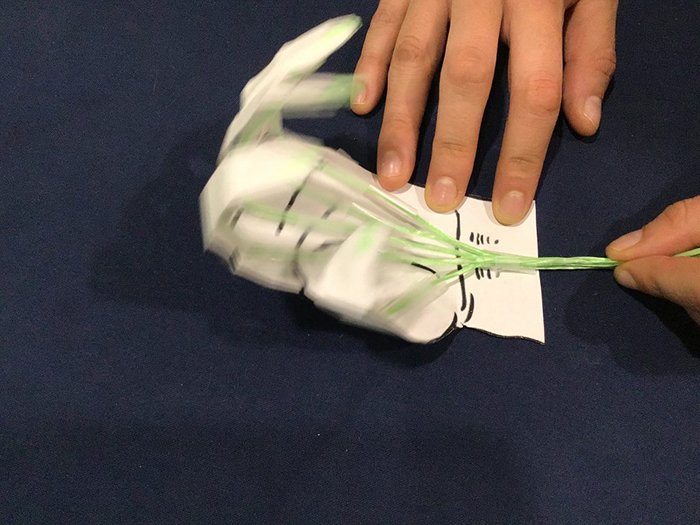 Paper hand model getting folded and held down by a hand