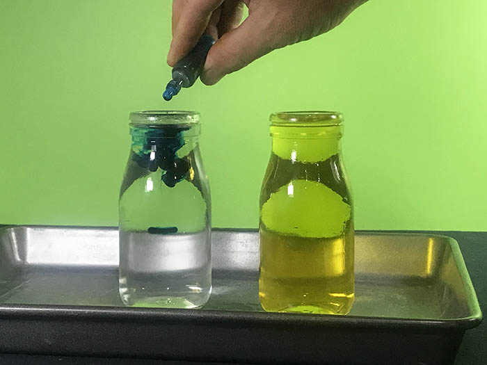Adding blue food colouring to one bottle of water with another bottle of water already coloured yellow