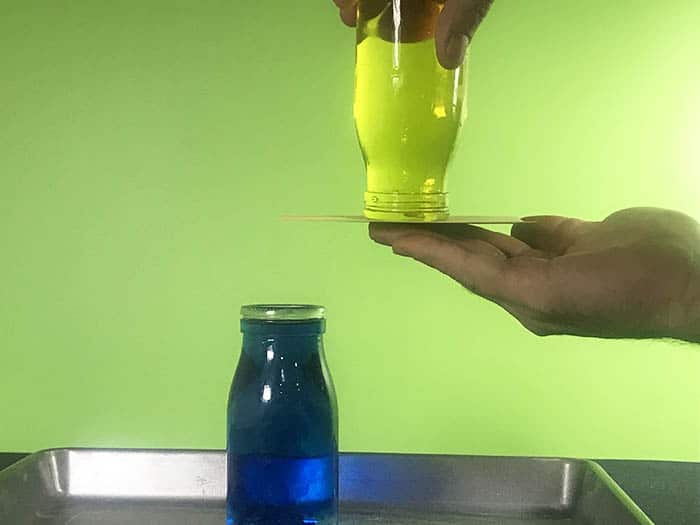 Upturned yellow water bottle with the index card underneath it being held up by a hand.