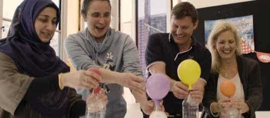 Teachers holding bottles with expanding balloons and smiling