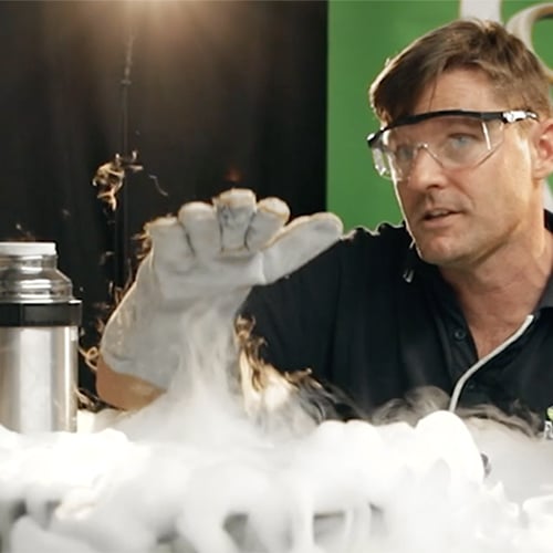 A cloud of liquid nitrogen vaur on a deask with a science presenter