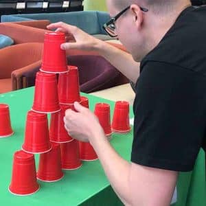 A man stacking red cups in a pyramid