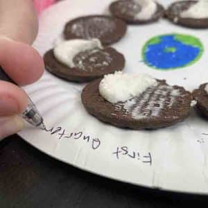 Writing the moon phases around the edge of paper plate with a pen