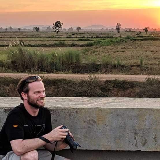 Ben Lewis with camera in hand with the Sun in the horizon