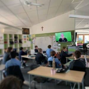 Students in a classroom watching a video conference by Fizzics Education