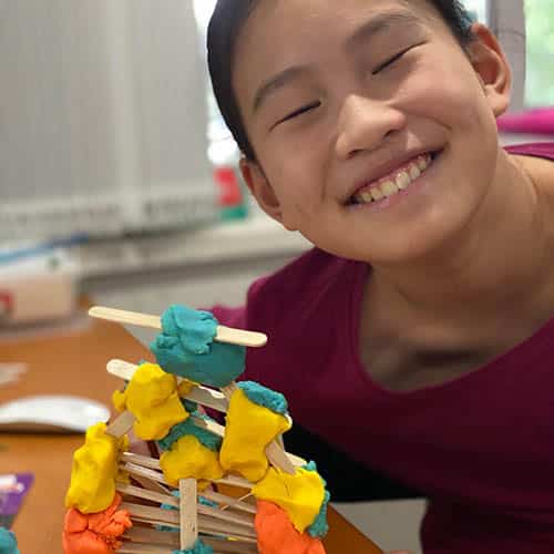 A smiling child in front of her tower creation