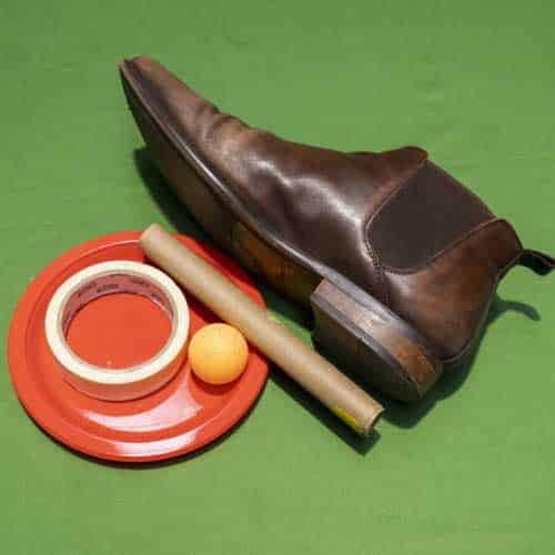 A boot, plate, cardboard roll, masking tape and a ping pong ball