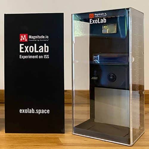 The ExoLab next to it's box. The Exolab looks like a clear plastic box with a camera & sensors