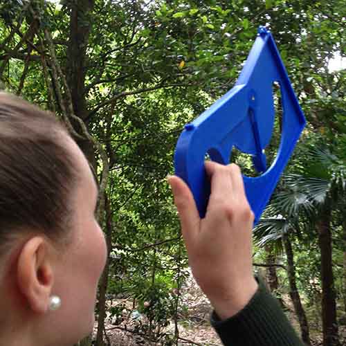 A woman using a clinometer to measure tree height