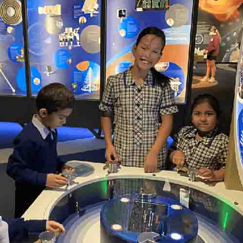 3 students standing at a science exhibit