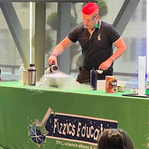 A science presenter pouring liquid nitrogen into a steel bowl