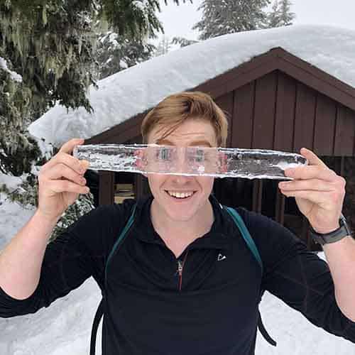 A man holding a length of ice and looking through it