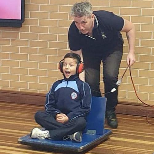 Child wearing earmuffs and riding a leafblower hovercraft