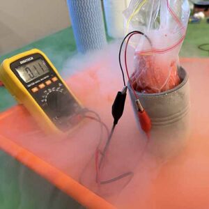 A multimeter and cup holding liquid nitrogen and an improvised insulation shield for a battery